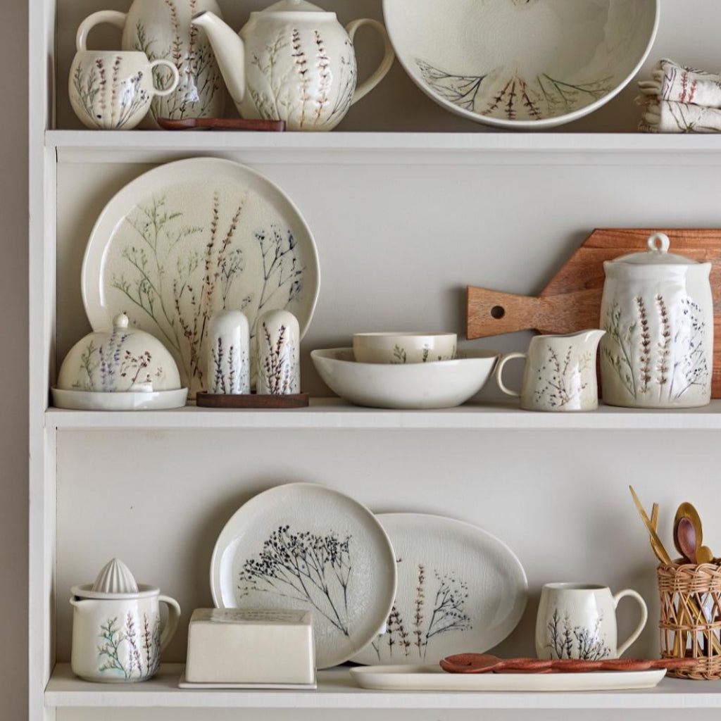 White ceramic dishes with floral patterns on a white shelf
