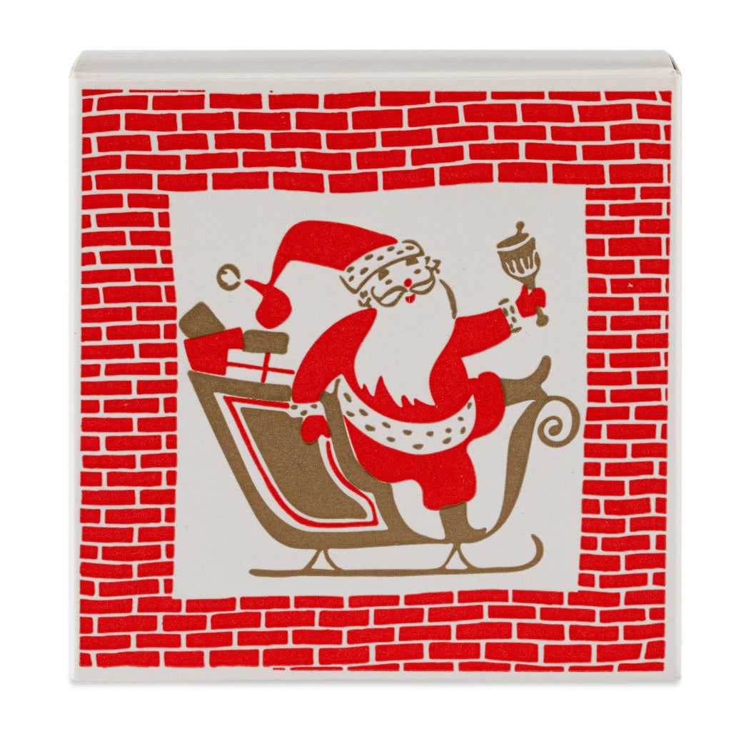 A vibrant square matchbox featuring a colourful illustration of Father Christmas in a red sleigh against a white and red brick background.
