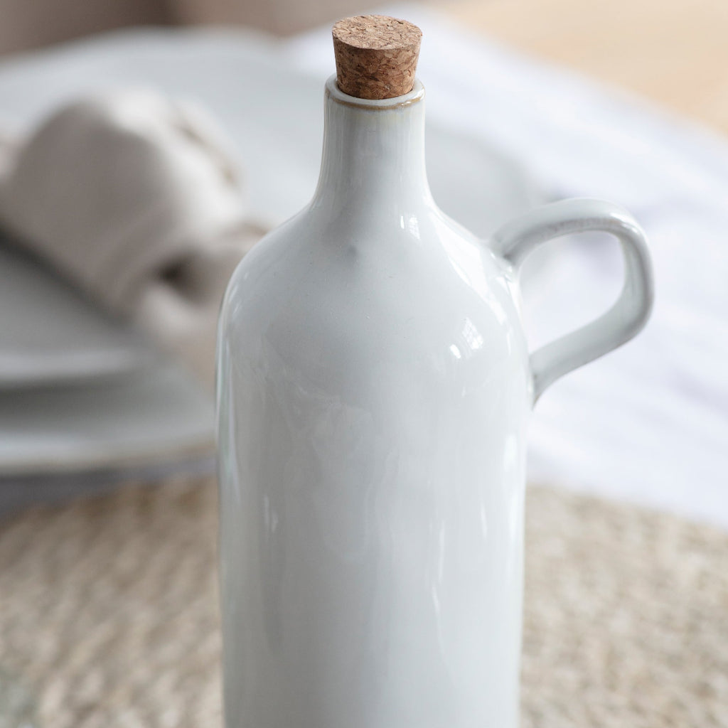 White ceramic bottle with cork stopper on a textured surface
