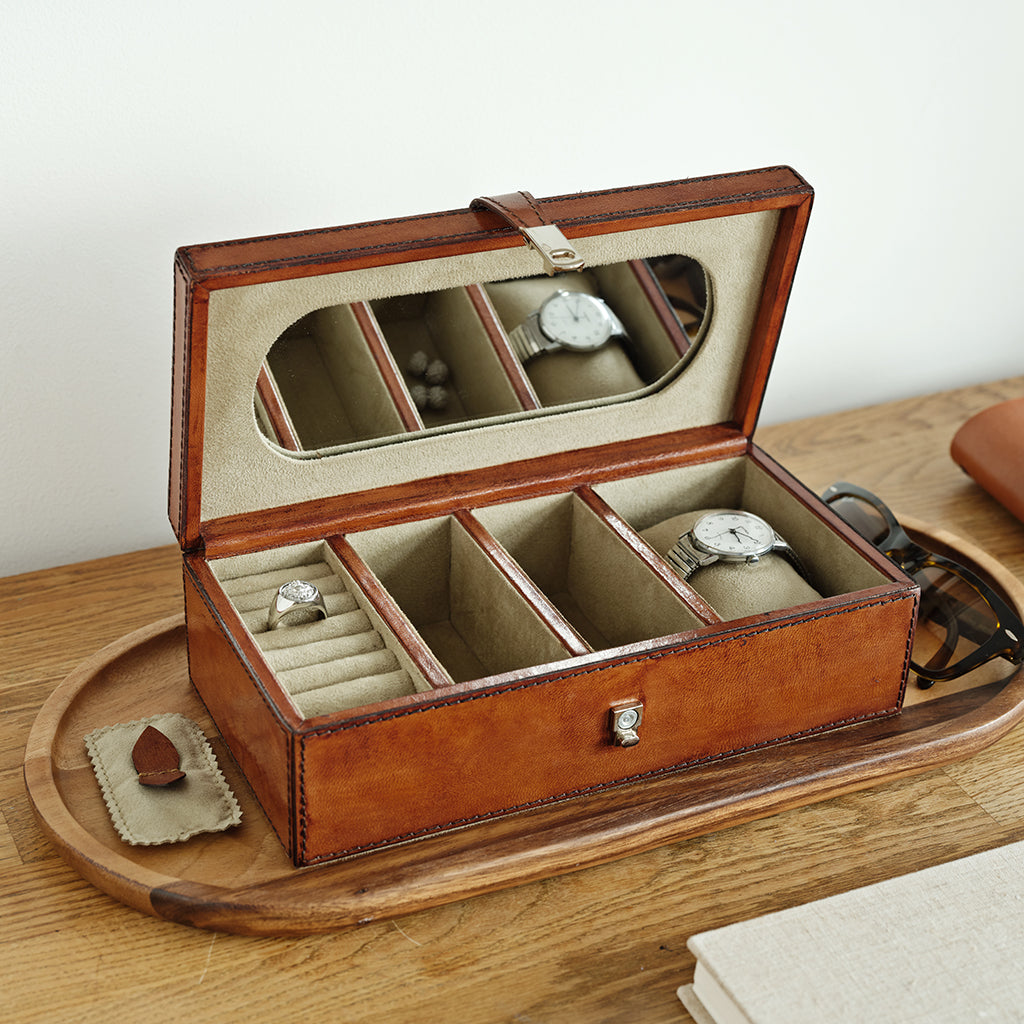 Leather jewellery box with watches and rings on a wooden surface