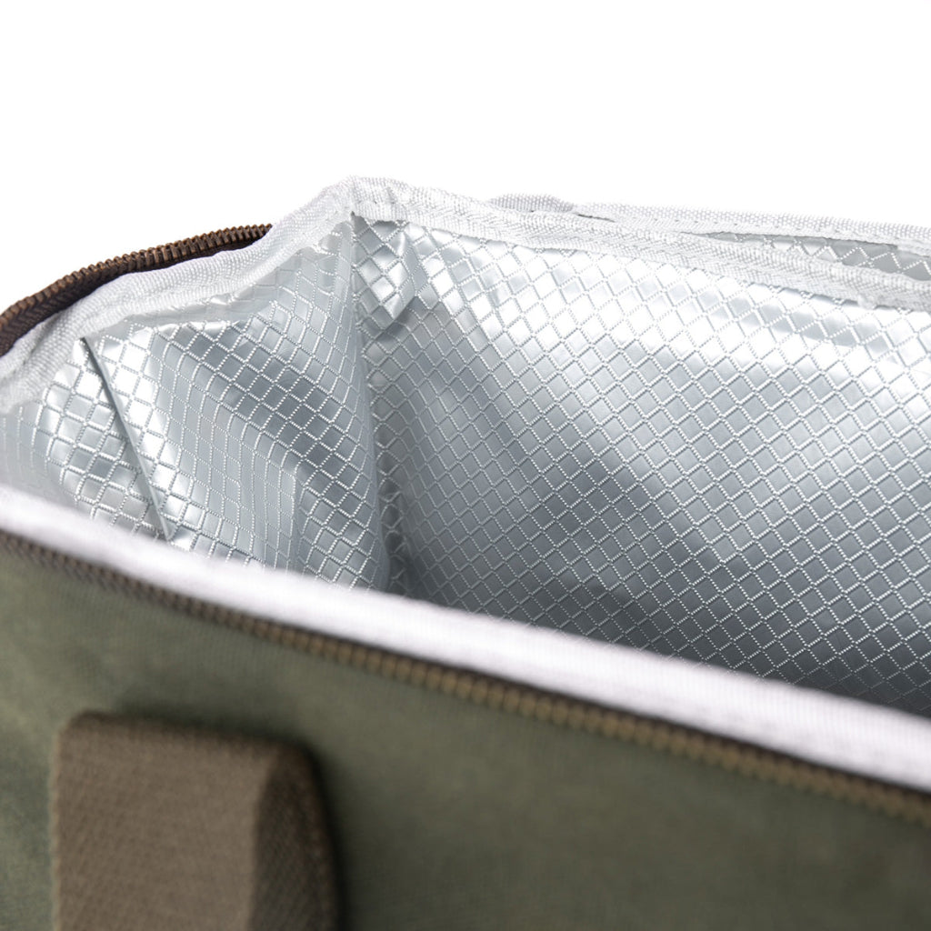 Close-up of an insulated bag's open top showing a silver reflective lining and a dark olive green exterior with a brown zipper.