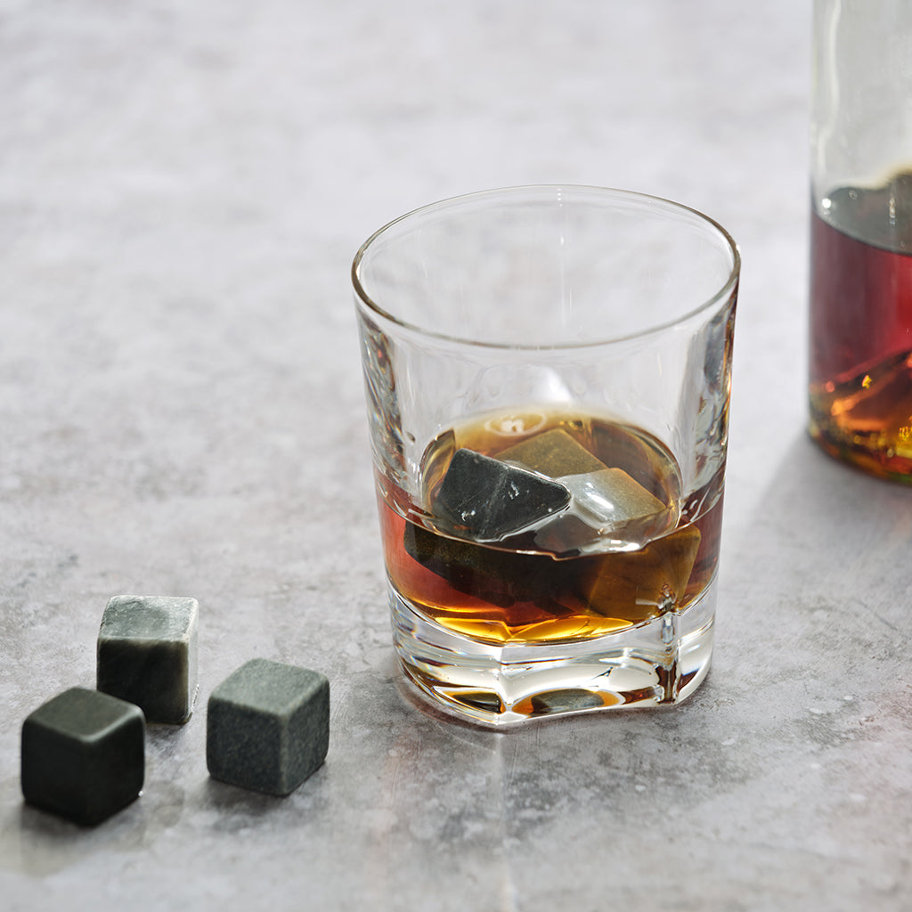 Glass of whiskey with whisky chillers on a marble surface