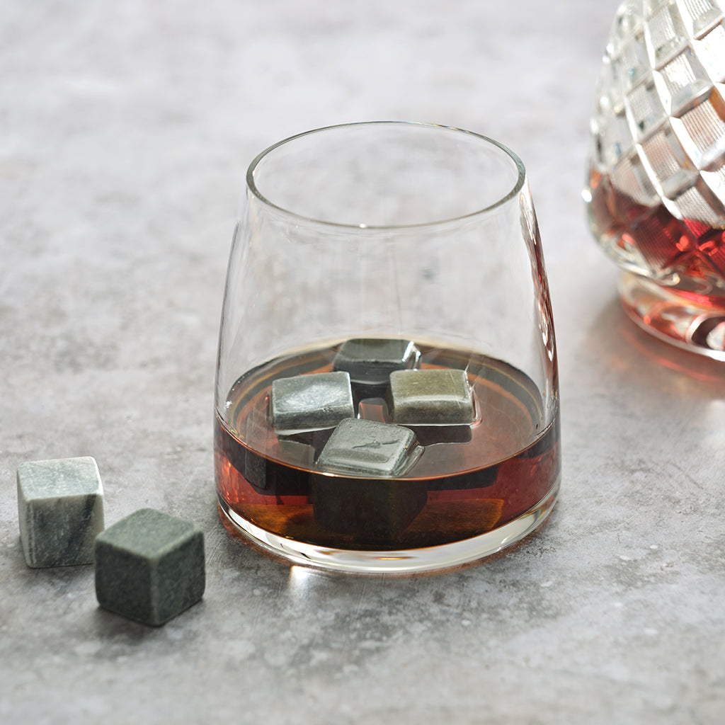 Glass of whiskey with whisky chillers on a grey surface