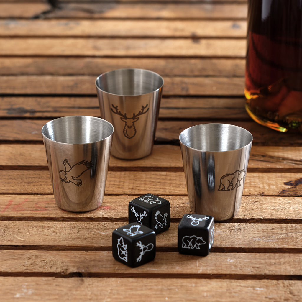 Four silver shot glasses with animal embossments on a wooden surface, accompanied by four black dice with animal designs.