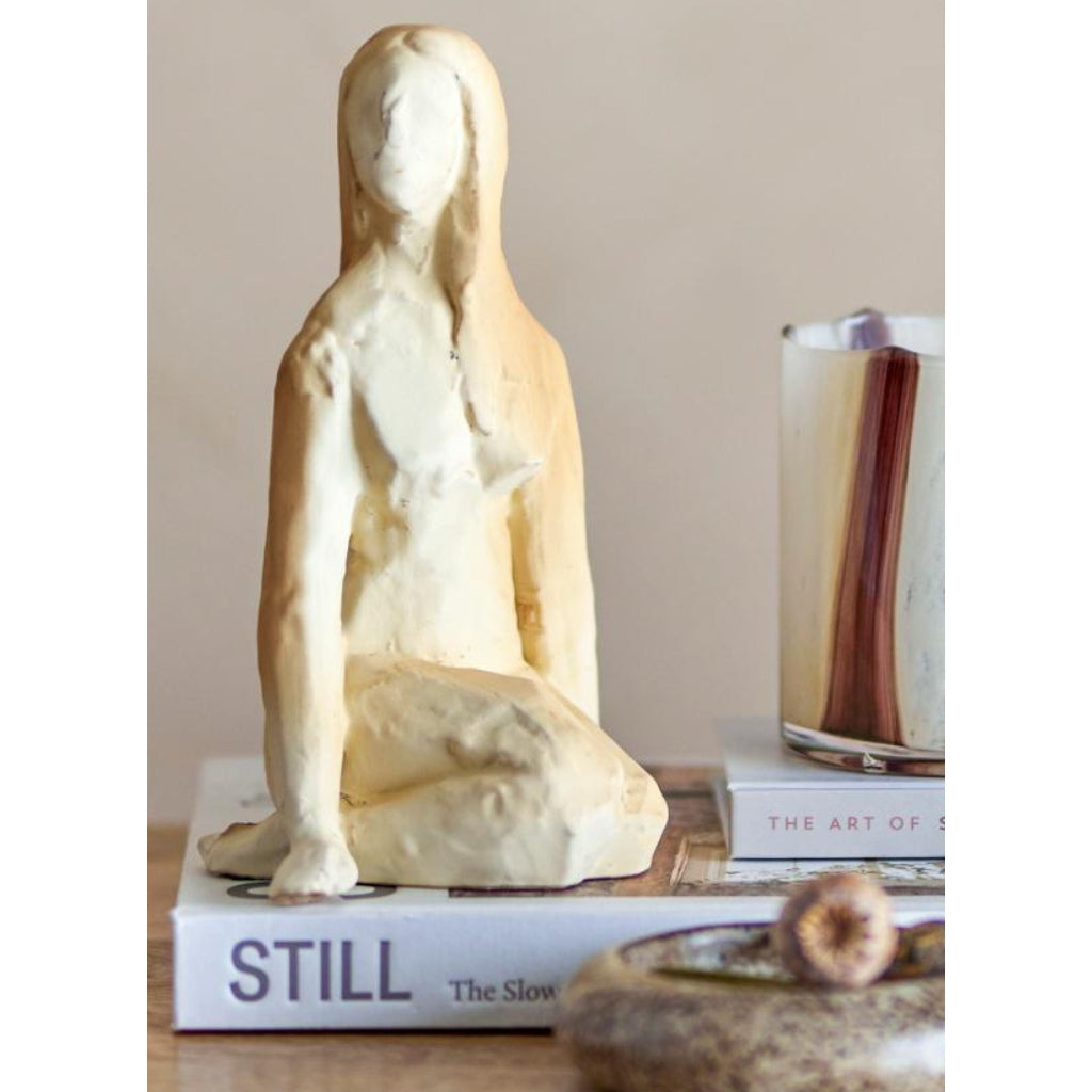 White sculpture on a book and a bowl in the background
