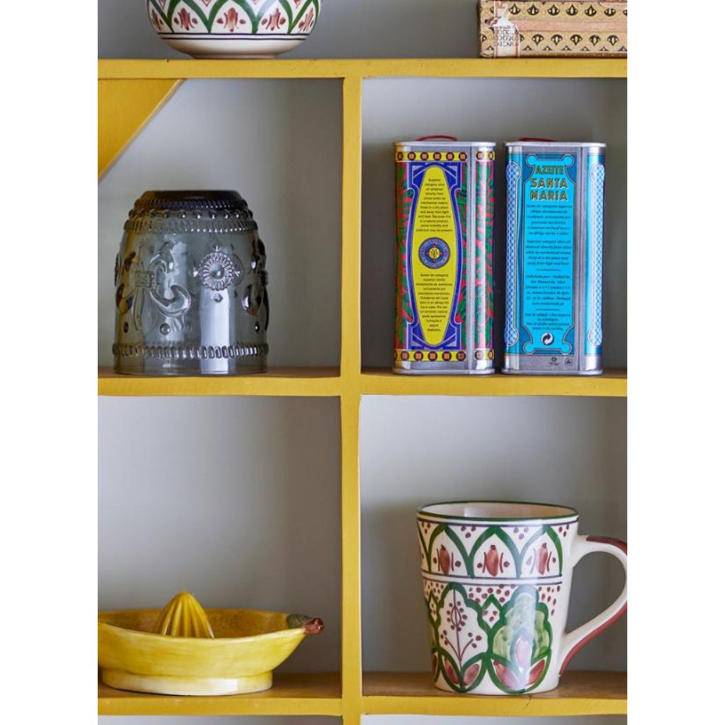 Decorative items on a yellow shelf including a mug, bowls, and tea tins.