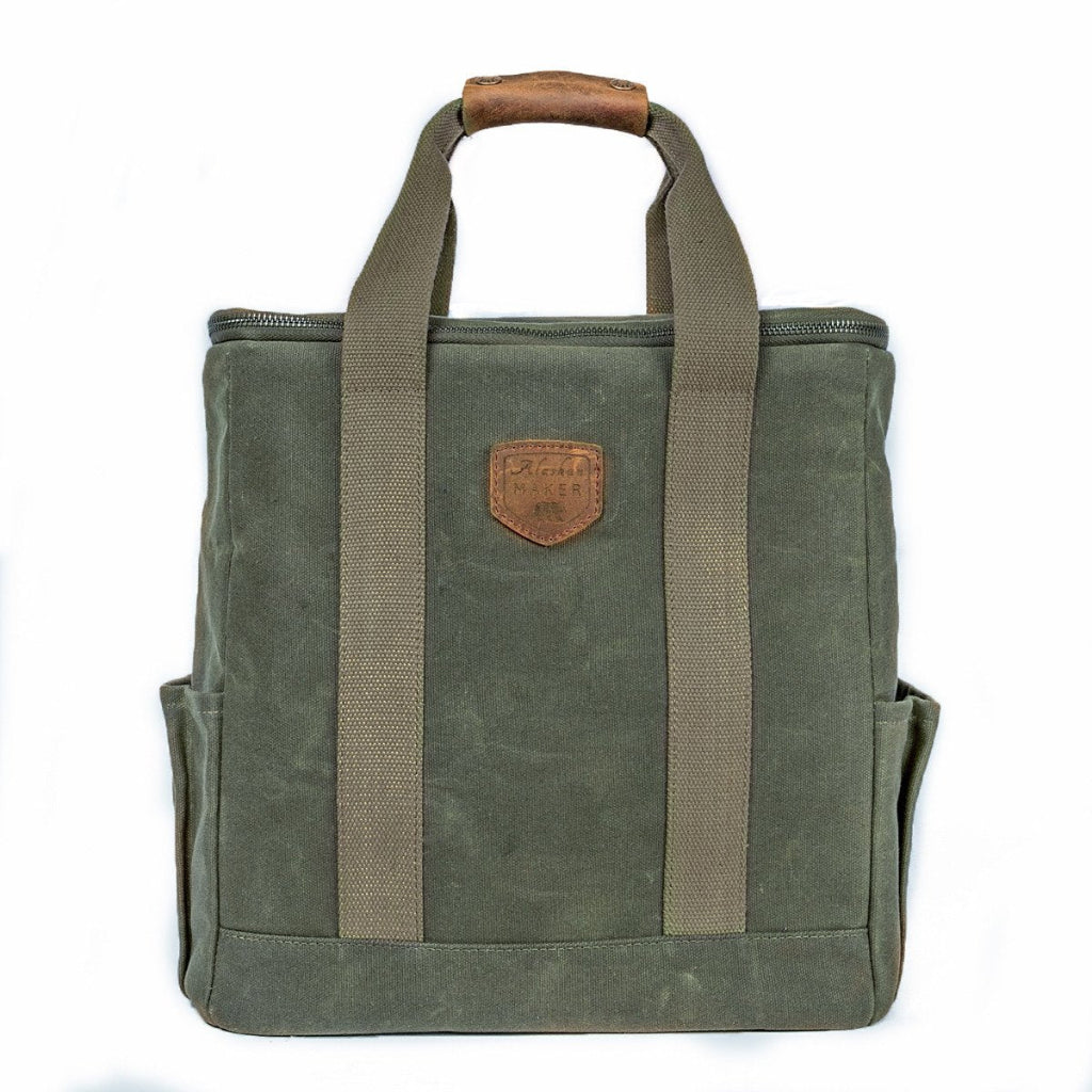 Green canvas bag with brown leather handle and strap on a white background