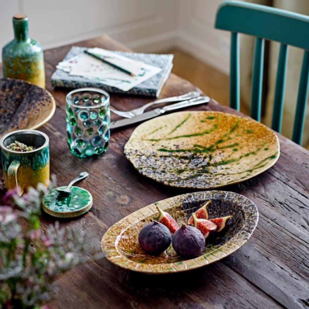 Dining table with ceramic plates, cups, and utensils in a home setting.