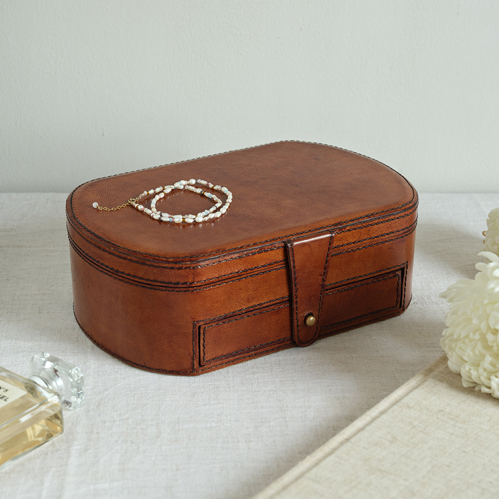 Brown leather jewellery box with a bracelet on a light surface