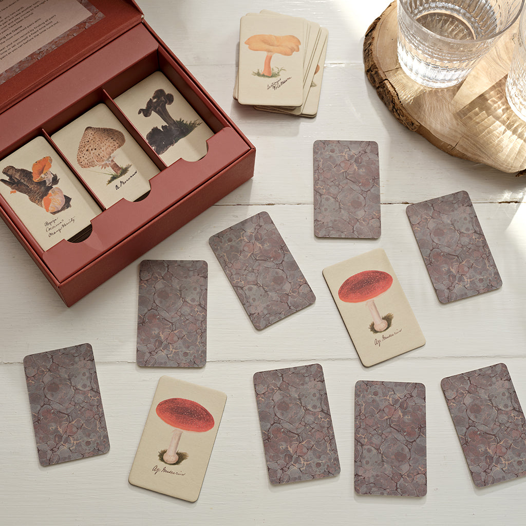 Set of playing cards with mushroom illustrations on a wooden surface.