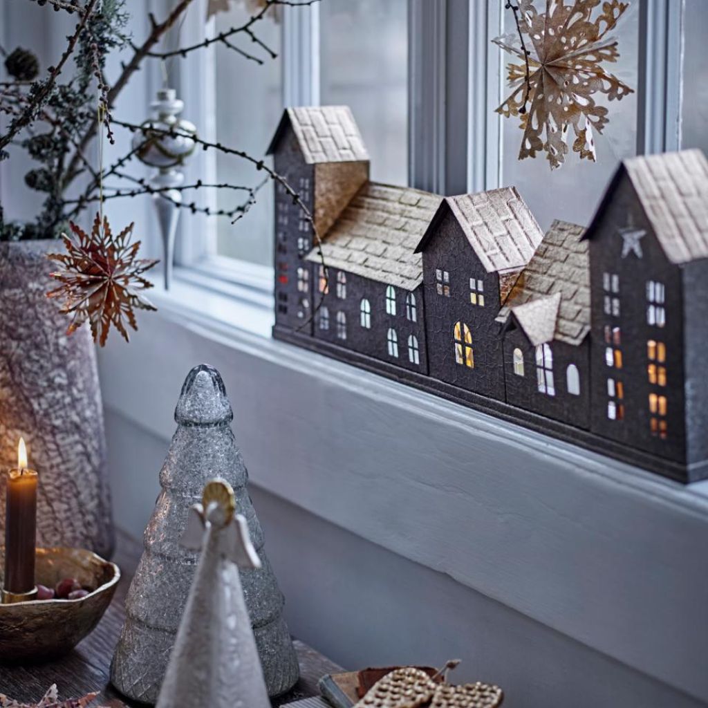 Decorative model of houses on a windowsill with festive decorations.