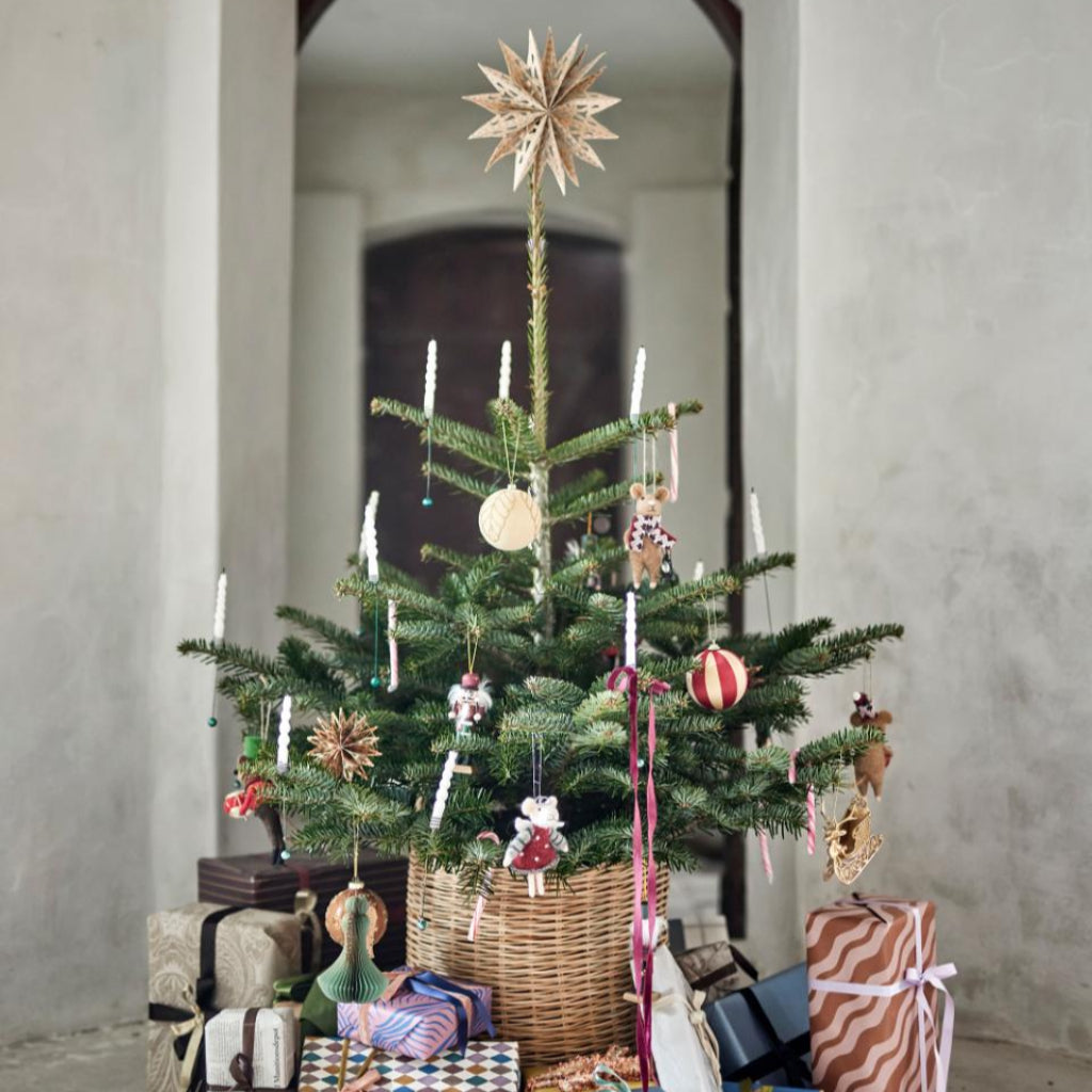 Decorated Christmas tree with ornaments and presents in a room with a brick archway.