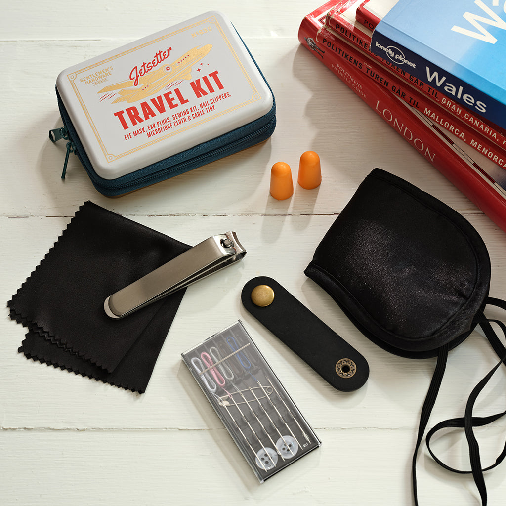 Travel kit with items including earplugs, nail clippers, and a cloth on a white surface.