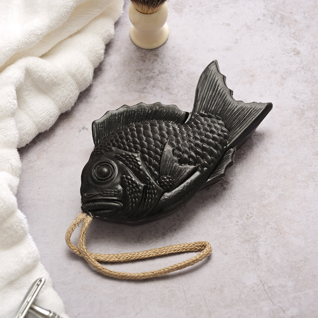 Black fish-shaped soap with a rope on a light grey surface