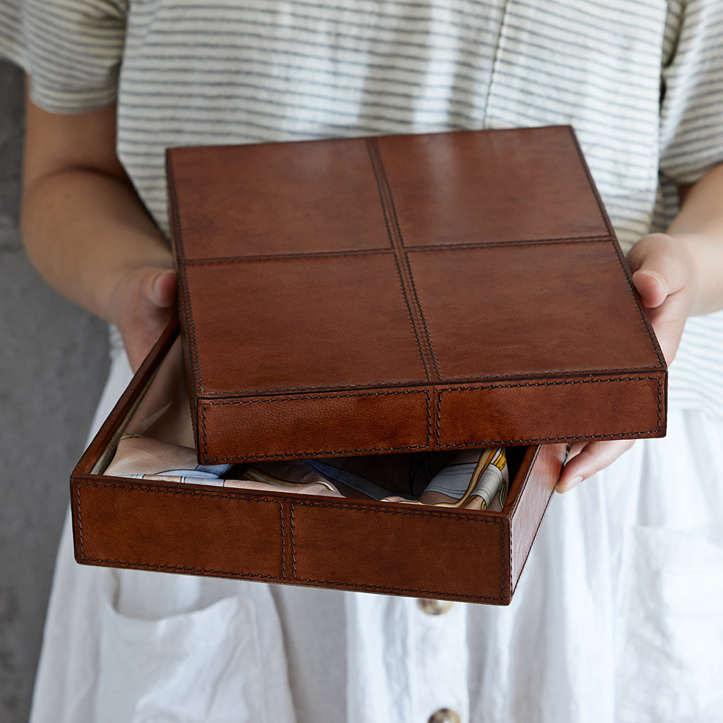 Leather gift box with lid partially off, being held 