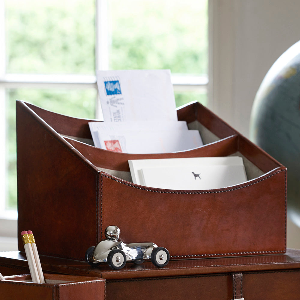 Leather letter rack with post in sitting on co-ordinating leather box file with a square leather pen pot.