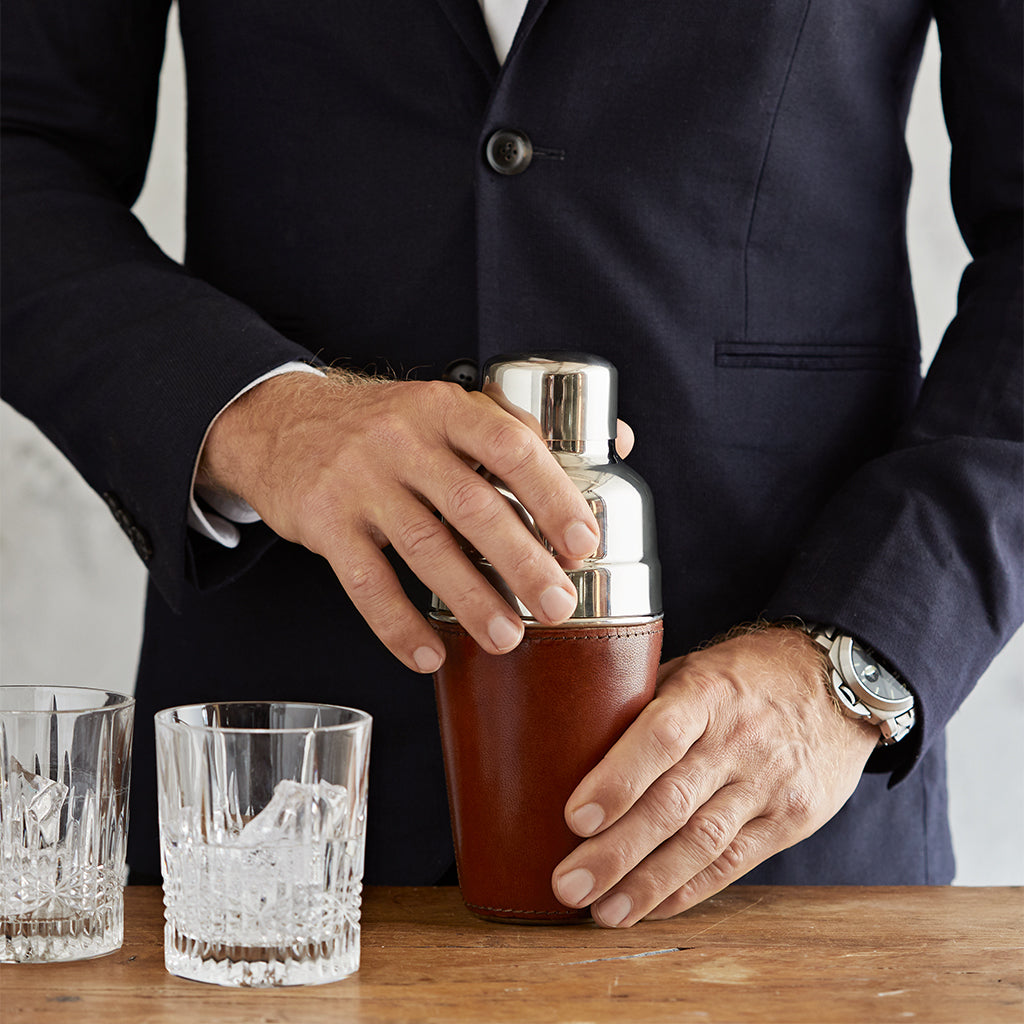 Conker brown leather cocktail shaker held by man with two glasses