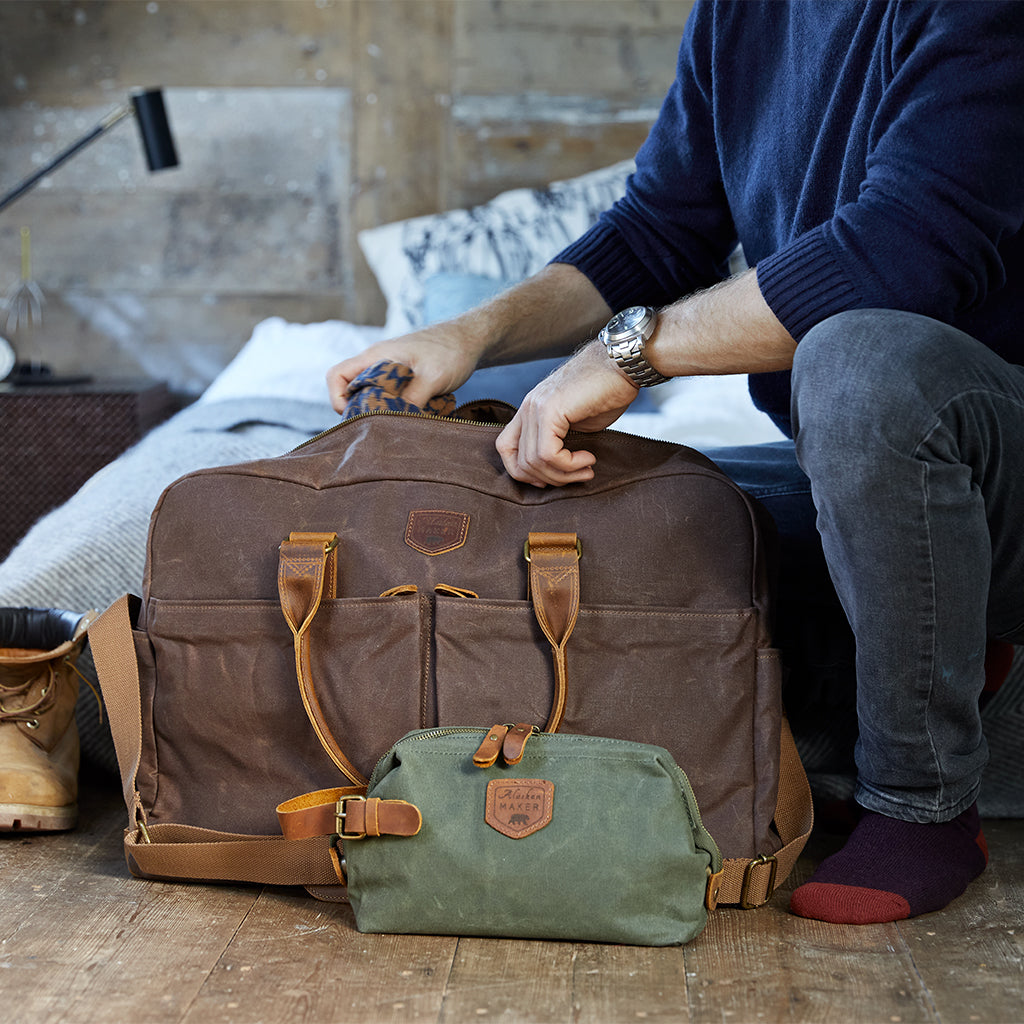 Brown waxed canvas weekend bag with a khaki toiletry bag.