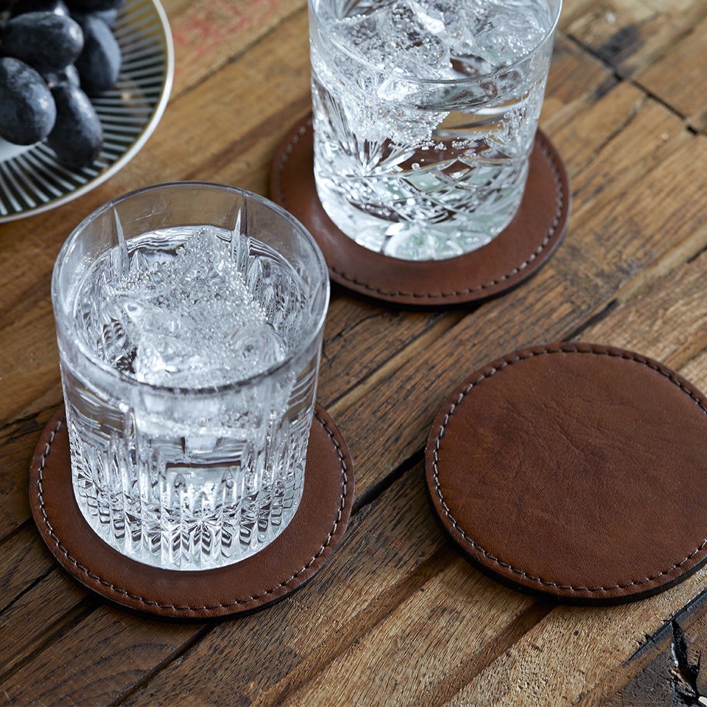 leather round single coaster with glass filled with water and ice