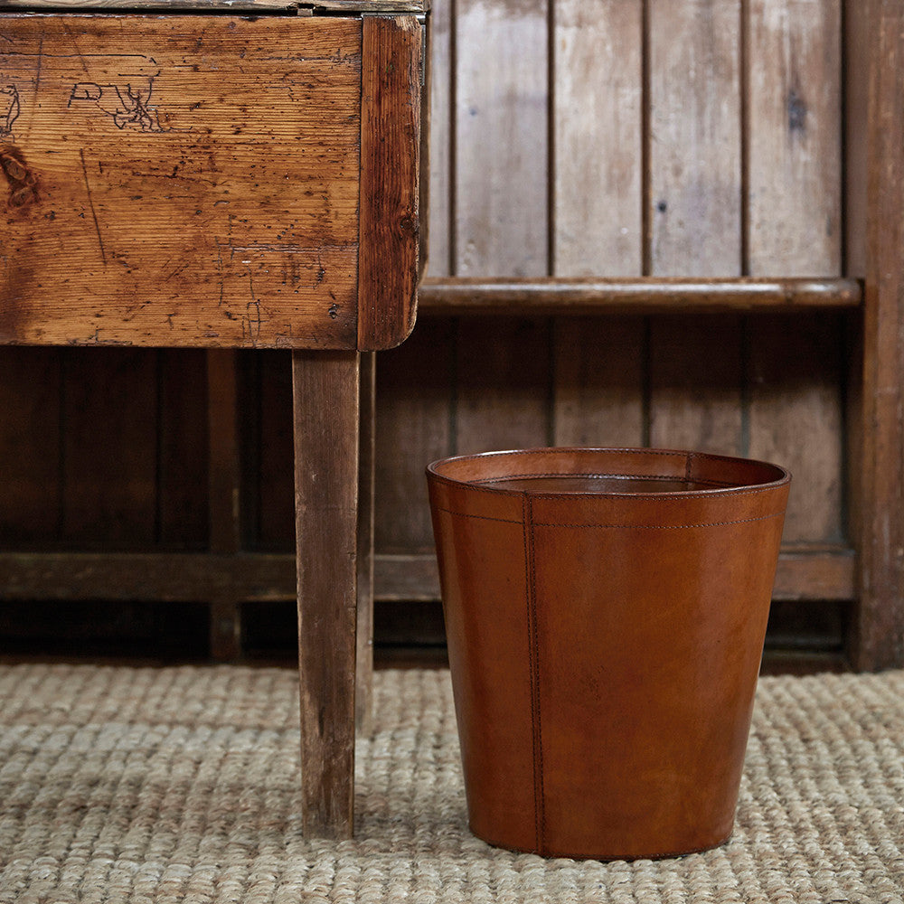 Leather waster paper bin in conker brown next to a desk