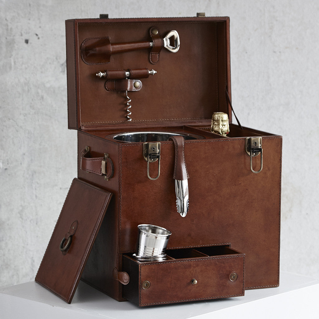 Leather drinks box with lid and drawer open, shown with the lid to the ice bucket against the side of the box, leather handled bar tool, corkscrew, bottle opener and ice tongs can al be seen.  