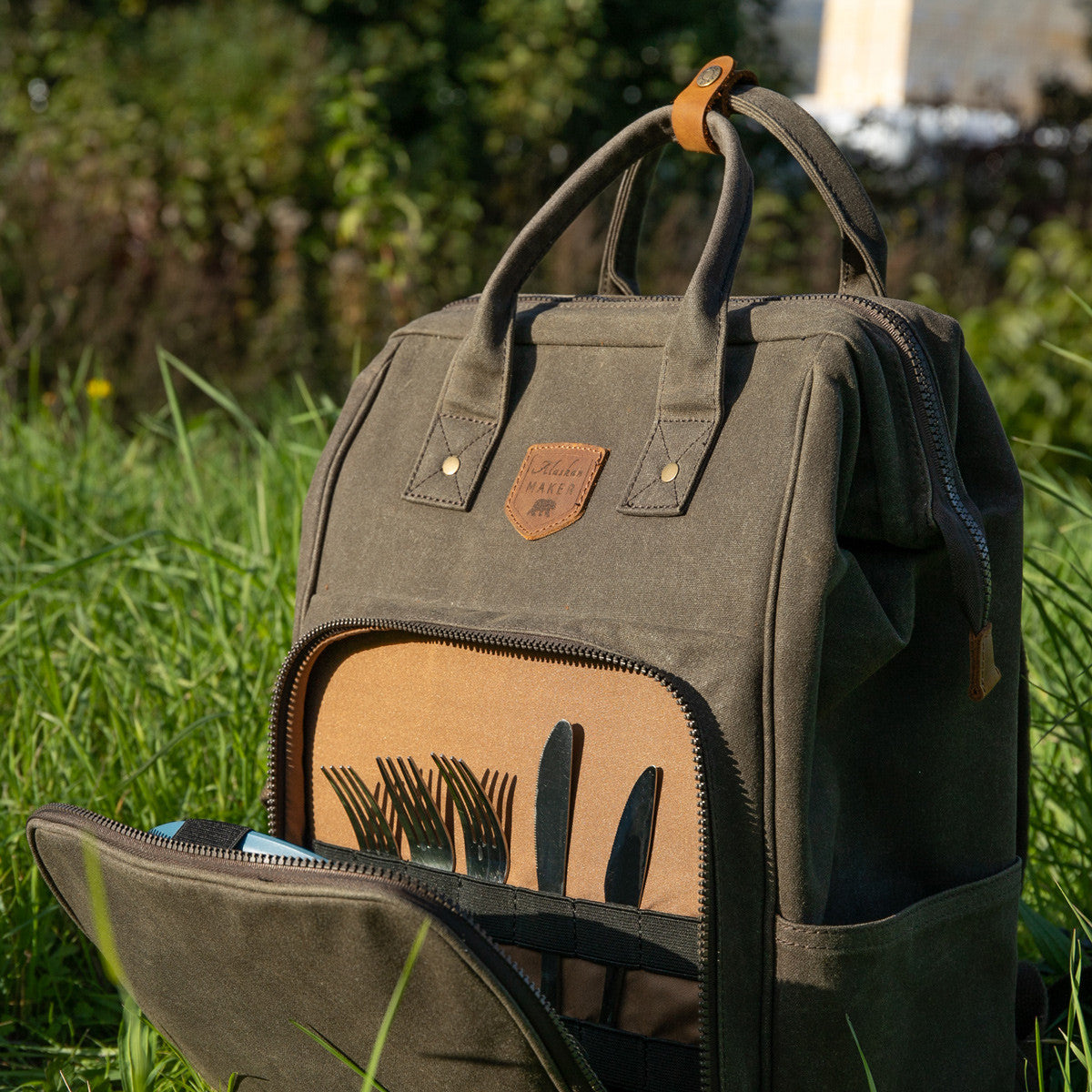 Waxed canvas bcakpack picnic cooler with zipped front pocket for storing plates and cutlery open