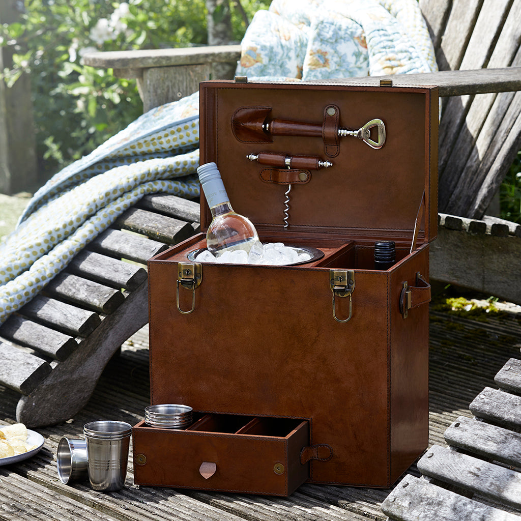 Leather drinks box open to show the ice bucket in use with a bottle of wine and the lid open allowing you to see the lether handled bottle opener and corkscrew, the bottom drawer is open and the nine metal cups that are included