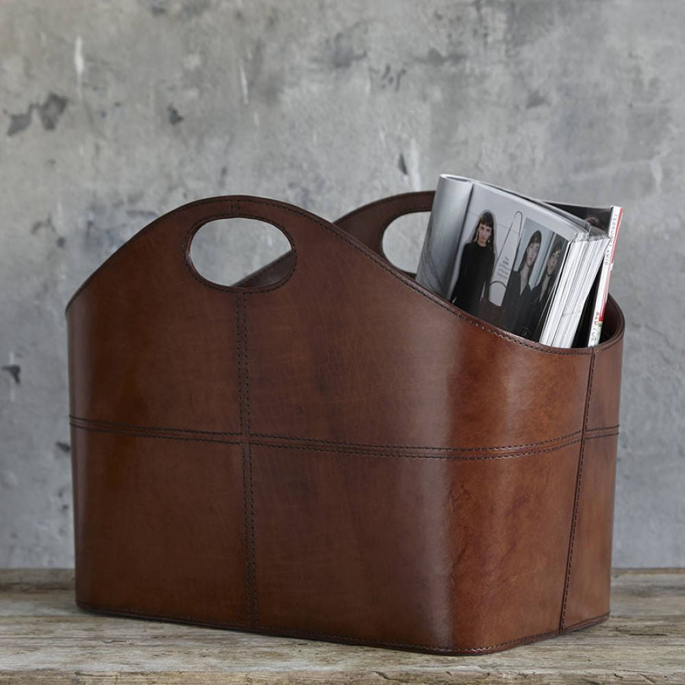 Curved leather conker brown storage basket  holding magazines.