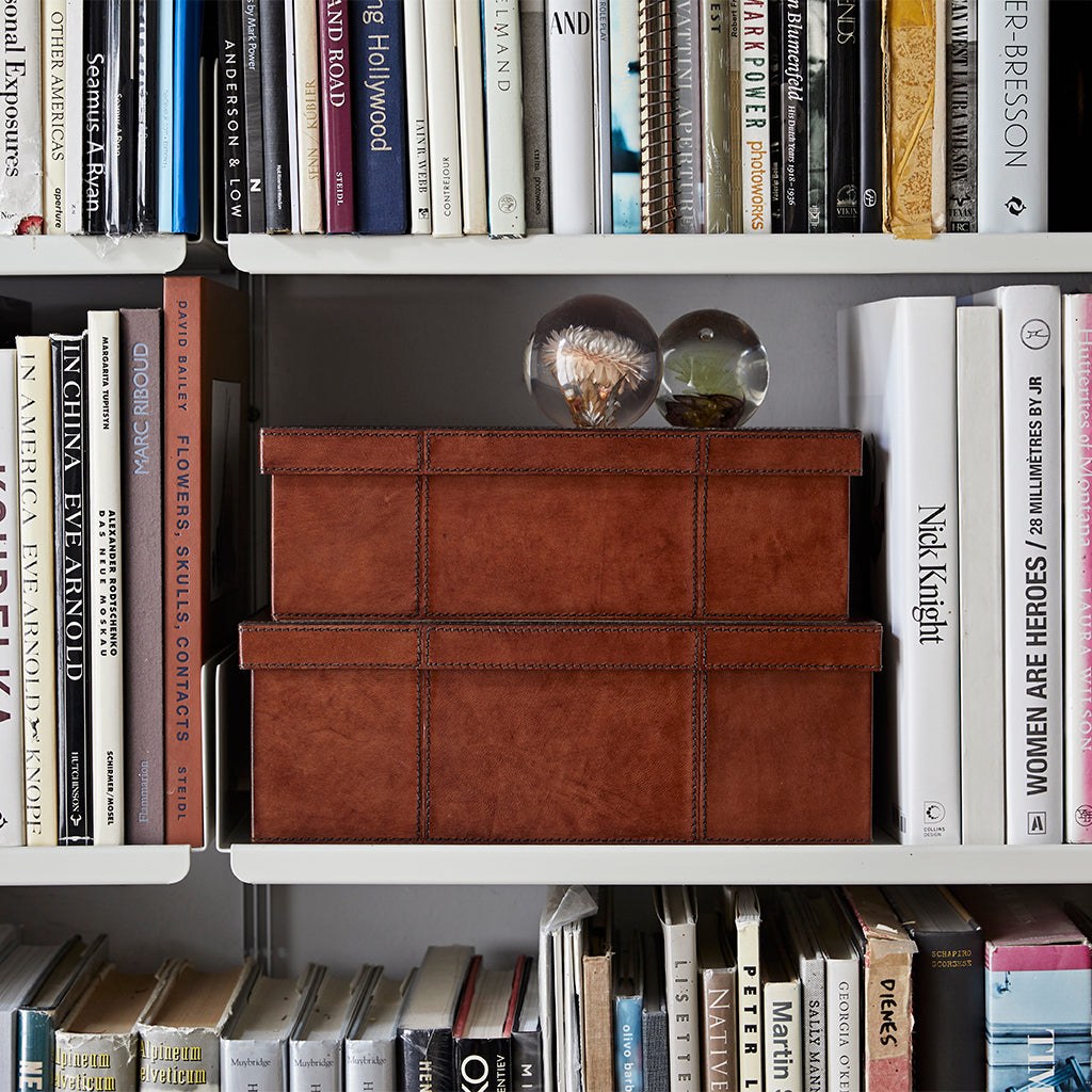 Leather shoe storage boxes in small and large stacked on top of each other in a bookcase